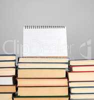 open blank notebook is standing on the stack of books