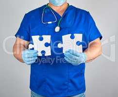 doctor in blue uniform and sterile latex gloves holds white big