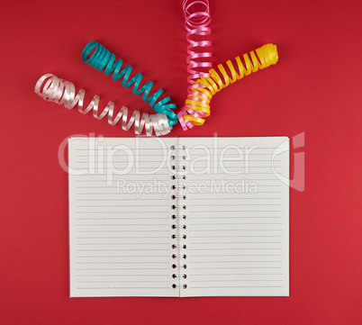 open notebook in line and multicolored serpentine on a red backg