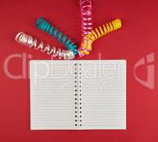 open notebook in line and multicolored serpentine on a red backg