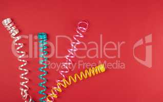 multicolored paper serpentine on red paper, festive background