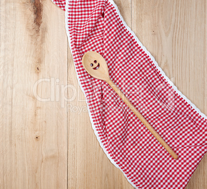 red towel and spoon on brown wooden background