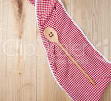 red towel and spoon on brown wooden background