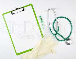green  medical stethoscope, gloves and green paper holder