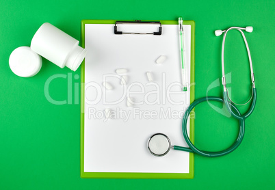 scattered white oval tablets from a plastic jar, stethoscope