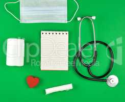open notebook in line with white sheets, medical mask, stethosco