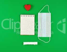 open notebook in line with white sheets, medical mask