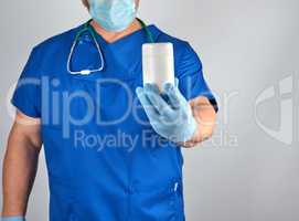 doctor in blue uniform is holding a plastic white jar with pills