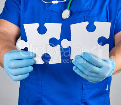 doctor in blue uniform  holds white big blank puzzles
