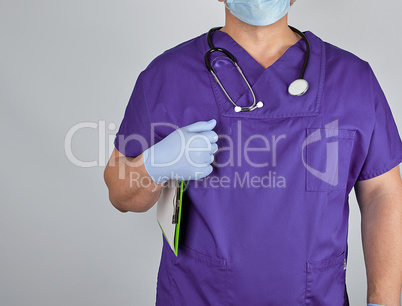 doctor in purple uniform and sterile latex gloves holds clipboar