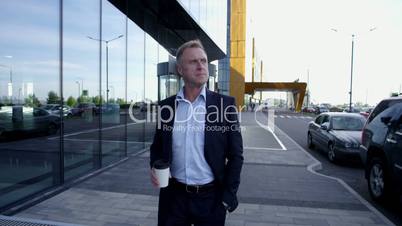 Mature businessman walking with coffee