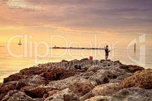 Fisherman on the rocks of South Marco Island Beach at Sunset wit
