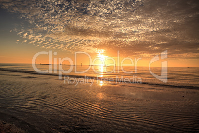 Ripples of waves under a sunset sky of red and orange at South M