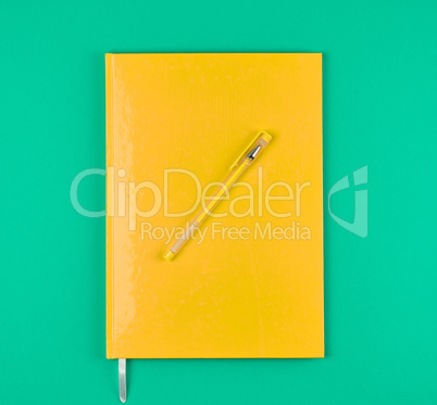 yellow closed notebook and yellow pen