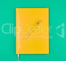 yellow closed notebook and yellow pen