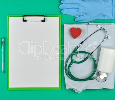 paper holder with empty white sheets, medical stethoscope, pills