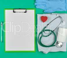 paper holder with empty white sheets, medical stethoscope, pills