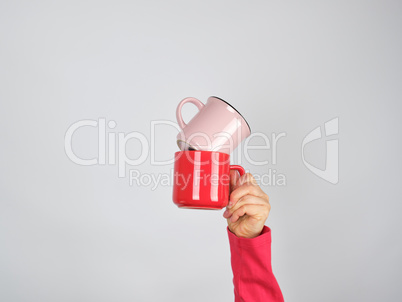 female hand holding a stack of ceramic mugs