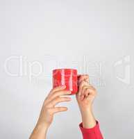 female hands hold a red ceramic mug