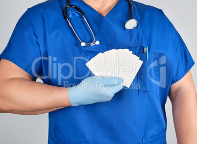 doctor in sterile latex gloves and blue uniform holds a blank wh