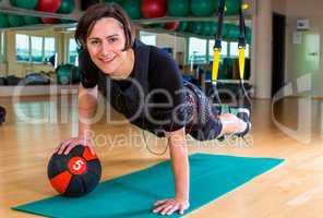 girl exercising with medicine ball and TRX lash in gym