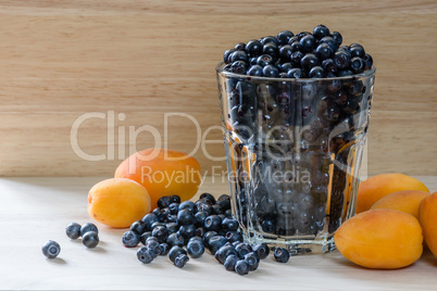 Blueberries in a glass with scattered berries and few apricot