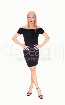 A serious looking blond woman standing in black outfit
