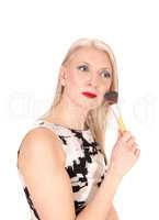 Beautiful blond woman fixing her makeup with a brush