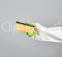 gloved hand holds  kitchen sponge