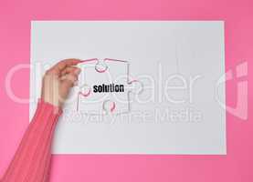 female hand holding white puzzle with the word solution, process