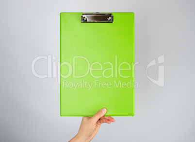 female hand holding a green clipboard  for clamping papers