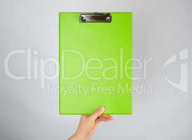 female hand holding a green clipboard  for clamping papers