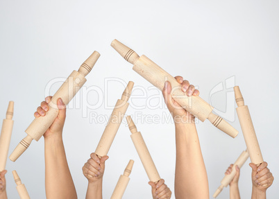 many hands raised up and holding kitchen wooden rolling pins