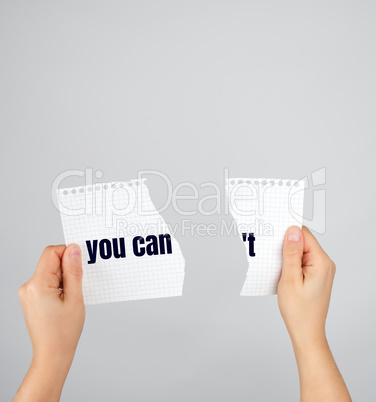 two hands holding a paper torn in half