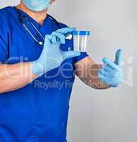 doctor in blue uniform and latex gloves is holding an empty plas