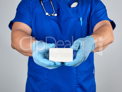 doctor in sterile latex gloves and blue uniform holds a blank wh