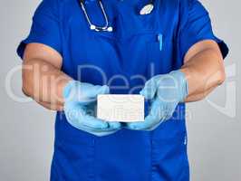 doctor in sterile latex gloves and blue uniform holds a blank wh