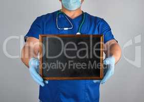 doctor in blue uniform and sterile latex gloves holding a wooden