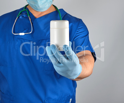 doctor in blue uniform is holding a plastic white jar with pills