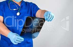 doctor in blue uniform and sterile latex gloves holds and examin