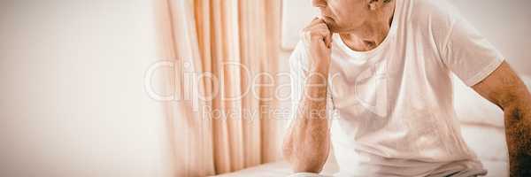 Worried senior man sitting on bed