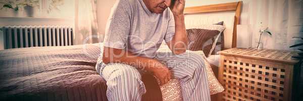 Frustrated senior man sitting on bed