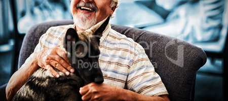 Portrait of smiling senior man sitting with puppy on chair