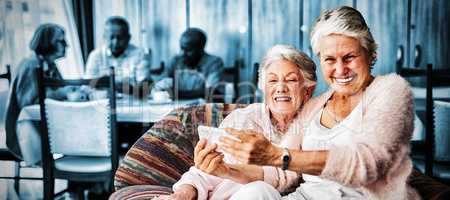 Portrait of smiling senior woman taking selfie with friend