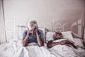 Senior woman getting disturbed with man snoring on bed