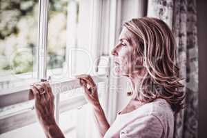 Thoughtful senior woman looking out from the window