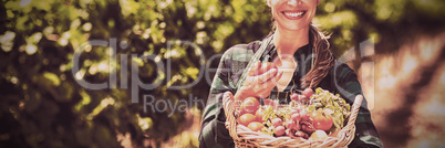 Portrait of happy female farmer holding a basket of vegetables