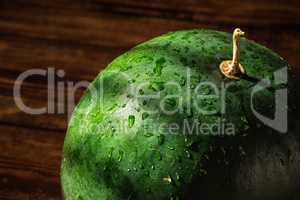 Green watermelon with sprays and shadows on peel