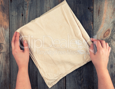 folded beige textile kitchen towel and two hands