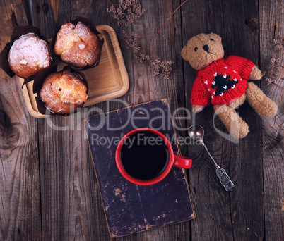 red ceramic mug with black coffee and baked muffins